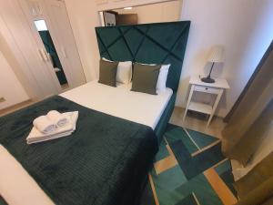 - une petite chambre avec un lit doté d'une tête de lit verte dans l'établissement Fundeni Apartments, à Bucarest