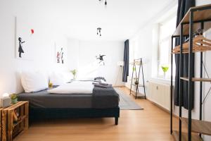 Schlafzimmer mit einem Bett mit weißen Wänden und Holzböden in der Unterkunft Ko-Living - Händel Stuben - Street Art Design Apartments - Altstadt - zentral - Küche - Smart TV - mehrere Apartments - bis zu 6 P in Halle an der Saale