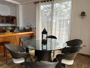 comedor con mesa de cristal y sillas en VILLA FLOREANA, en Puerto Velasco Ibarra