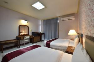 a hotel room with two beds and a mirror at Jiuning Business Hotel in Tainan