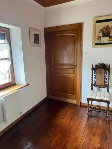 um quarto vazio com uma cadeira e uma porta de madeira em Maison Ray Sur Saône em Ray-sur-Saône