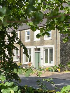 a brick house with a green door on a street at 1 The Cairn Kilmartin - Beautiful Victorian Flat, Pet Friendly in Kilmartin