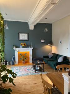 1 The Cairn Kilmartin - Beautiful Victorian Flat, Pet Friendly في Kilmartin: غرفة معيشة مع أريكة خضراء ومدفأة