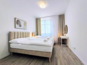een slaapkamer met een bed met witte lakens en een raam bij Cinnamon - Brand New - Presidential Garden - Free Parking in Bratislava