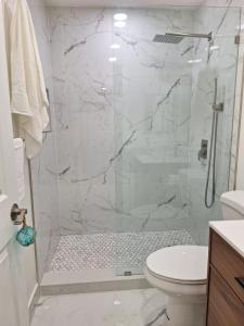 a white bathroom with a shower with a toilet at Casa Del Sol in Lauderhill