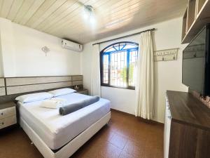 ein Schlafzimmer mit einem Bett, einem Fernseher und einem Fenster in der Unterkunft Casa na Praia dos Ingleses para até 12 pessoas in Florianópolis
