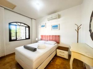 ein Schlafzimmer mit einem Bett mit Schreibtisch und einem Fenster in der Unterkunft Casa na Praia dos Ingleses para até 12 pessoas in Florianópolis