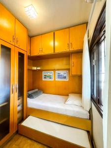 Habitación pequeña con 2 camas y armarios de madera. en Casa na Praia dos Ingleses para até 12 pessoas, en Florianópolis