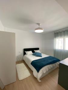 a white bedroom with a large bed with a blue blanket at ARENA & MAR in El Campello