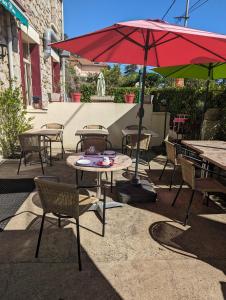 un patio con mesas, sillas y una sombrilla roja en Auberge Des Pins, en Aubenas