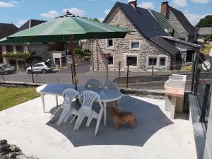 une table, des chaises et un chien sous un parasol dans l'établissement La Cordonnerie, à Messeix