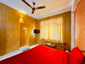 a room with a red bed with a ceiling fan at Grand view lodge and Restaurant Dharamshala - Partial Prepayment required to confirm booking in Dharamshala