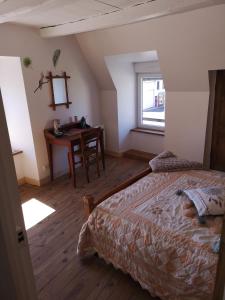 a bedroom with a bed and a desk and a window at La Cordonnerie in Messeix