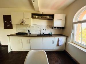 cocina con armarios blancos, fregadero y ventana en Apartmány 68, en Kámen