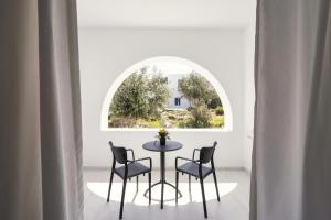a table and chairs in a room with a window at Bedspot Apartments Paros in Naousa