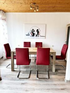 une salle à manger avec une table en bois et des chaises rouges dans l'établissement Nordseebriese, à Hage