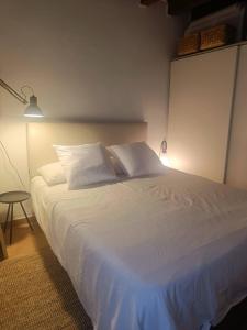 un letto con lenzuola e cuscini bianchi in una camera da letto di Tortona Design Navigli Milan a Milano