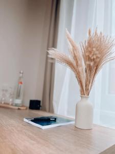 un vase blanc recouvert de plumes sur une table dans l'établissement Dions Rooms, à Norderney