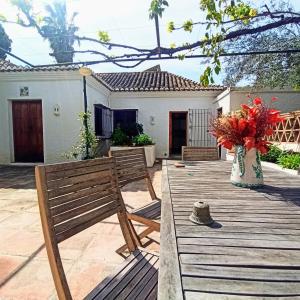 eine Holzterrasse mit zwei Bänken und einer Vase aus Blumen in der Unterkunft El Cortijo de Marie in Granada