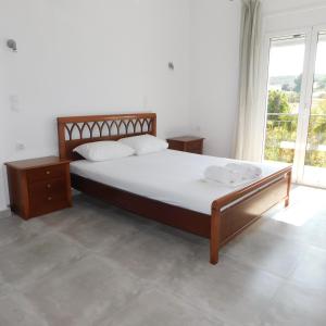 um quarto com uma cama e uma grande janela em Κωνσταντίνος Έλενα Studios em Pefki