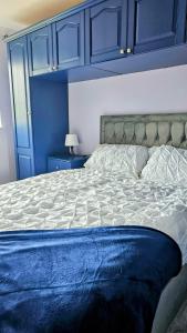 a bedroom with a large bed with blue cabinets at StayViva - Spacoius 3 BR House - Garden, Games Room, Parking near Town Centre and Train station in Bracknell