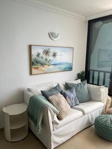 a living room with a white couch with pillows at Sol y Sea Holiday Homes Don Paco in Patalavaca +1 photo