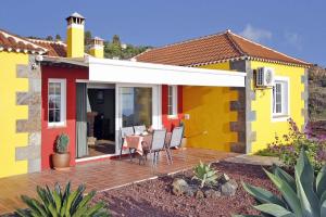 a yellow house with a table and chairs on a deck at Ferienhaus mit Privatpool für 7 Personen ca 130 qm in Tijarafe, La Palma Westküste von La Palma in Tijarafe