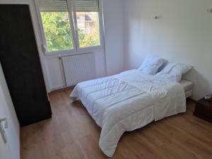 um quarto com uma cama com lençóis brancos e uma janela em location appartement 80m2 à Rombas em Rombas