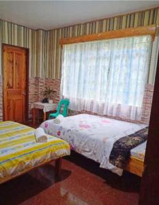 een slaapkamer met 2 bedden en een raam bij An Escape to a Semi-Countryside Retreat - SEE TOO VILLE- Nature Lodging Home in Sagada