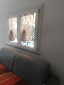 ein Sofa in einem Zimmer mit zwei Fenstern in der Unterkunft Studio für 4 Personen ca 60 qm in Porto Torres, Sardinien Sassarese in Porto Torres