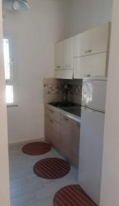 eine Küche mit einem weißen Kühlschrank und roten Matten auf dem Boden in der Unterkunft Studio für 4 Personen ca 60 qm in Porto Torres, Sardinien Sassarese in Porto Torres