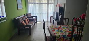 sala de estar con 2 sillas, sofá y TV en Apartamento PRAIA, en Cabo Frío