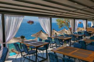 un ristorante con tavoli e sedie e l'oceano di Fabeno Villa a Sarandë