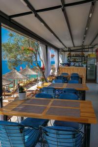 a restaurant with wooden tables and chairs and the beach at Fabeno Villa in Sarandë