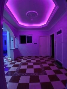 um quarto vazio com um tecto roxo e um piso xadrez em Dar zahra em Aourir