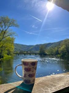 a coffee cup sitting on a table in front of a river at Vacation Home Pliva in Šipovo