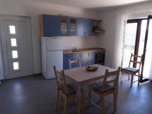 eine Küche mit einem Tisch und Stühlen sowie eine Küche mit blauen Schränken in der Unterkunft Ferienwohnung für 4 Personen ca 48 m in Privlaka, Dalmatien Norddalmatien in Privlaka