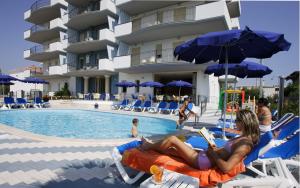 a woman laying on a beach chair next to a swimming pool at Residence il Girasole 1 in Alba Adriatica