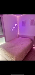 a pink bed with a string of lights on it at Chambre à louer avec salle de bain privative in Carrières-sous-Poissy +1 photo