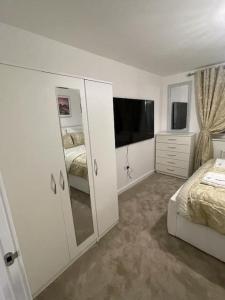 ein weißes Schlafzimmer mit einem Bett und einem TV in der Unterkunft Luxurious 4 Bed House Manor View in Wavendon