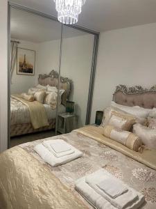 1 Schlafzimmer mit 2 Betten und einem großen Spiegel in der Unterkunft Luxurious 4 Bed House Manor View in Wavendon