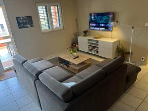 a living room with a couch and a tv at Red House Apartment With Swimming Pool in Vinišće