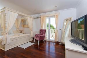 a bedroom with a white bed and a tv at Ferienhaus mit Privatpool für 8 Personen ca 200 qm in Stanković bei Orebić, Dalmatien Süddalmatien in Orebić