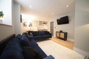 Una sala de estar con un sofá azul y un televisor. en Pass the Keys Apartment 4 Old Conservative Club in Historic Town, en Caernarfon