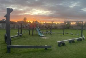 a playground with a slide in a field with the sunset at 348 Golden Sands in Withernsea