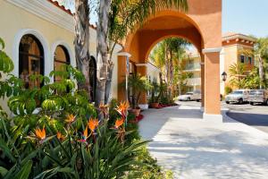 a building with an archway and flowers next to a sidewalk at Cortona Inn and Suites Anaheim Resort in Anaheim