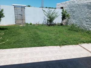 une cour herbeuse avec une clôture et un bâtiment dans l'établissement Dar allouch, à Hennchir Ksar Rhaleb