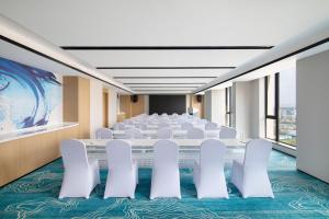 Fairfield by Marriott Chengdu Hi-Tech Zone في تشنغدو: قاعة اجتماعات مع كراسي بيضاء وطاولة