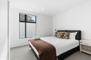 a white bedroom with a bed and a window at Brand new 3 Bed 3 Bath in Christchurch