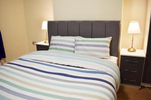 a bed with a blue and white striped blanket at Birmingham City Centre Room in edgbaston near stadium, Free Parking in Birmingham +15 photos